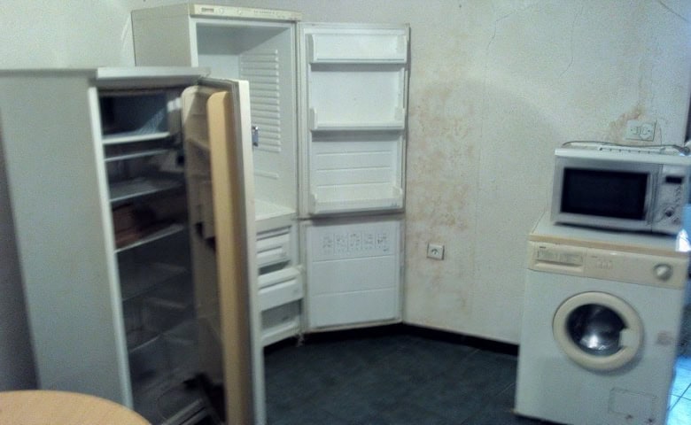 Interior view of a small kitchen with an open refrigerator, microwave, and washing machine.