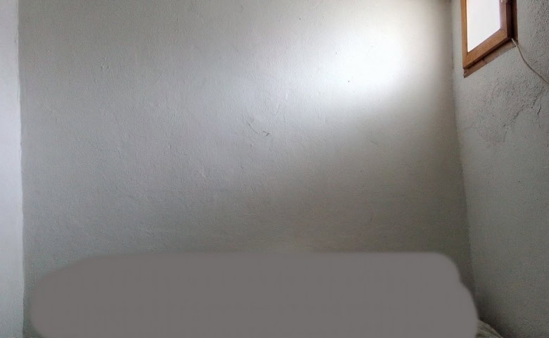 Interior view of a rustic village property in Zujar, Granada, showing simple walls and a small windo.