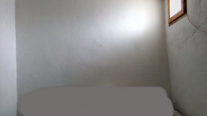 Interior view of a rustic village property in Zujar, Granada, showing simple walls and a small windo.