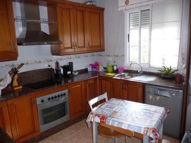 Charming kitchen with wooden cabinets and modern appliances in a village home in Zujar, Granada.