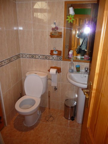 Bathroom with toilet, sink, and mirror in a traditional village home.