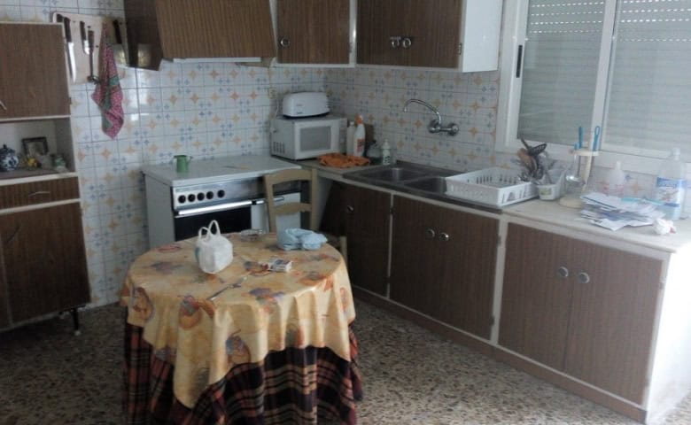 Interior view of a traditional village kitchen in Zujar, Granada with wooden cabinets and a small di.