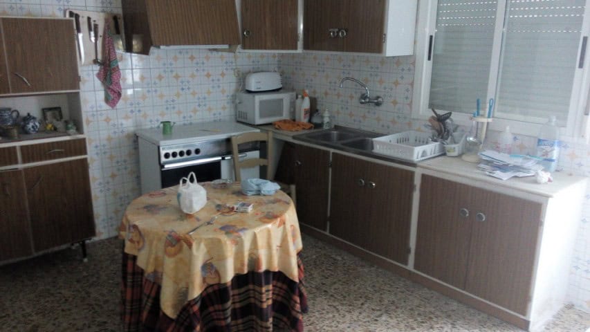 Interior view of a traditional village kitchen in Zujar, Granada with wooden cabinets and a small di.