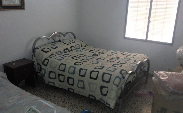 Charming village property in Zujar, Granada, featuring a cozy bedroom with metal bed frame and natur.