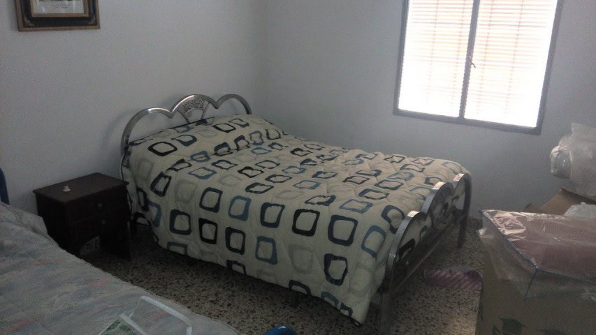 Charming village property in Zujar, Granada, featuring a cozy bedroom with metal bed frame and natur.