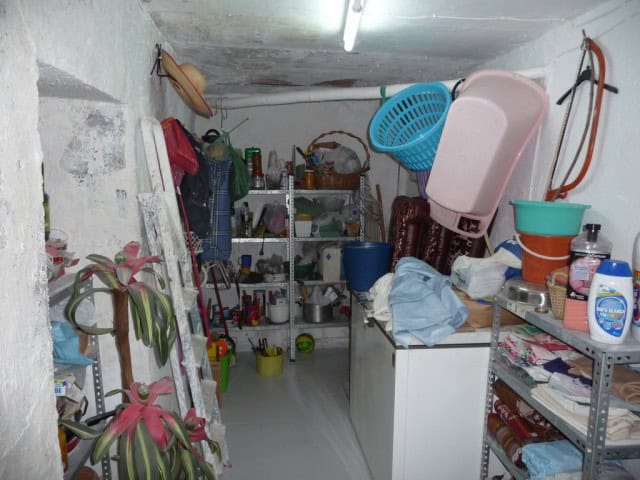 Interior of a rustic village home in Zujar, Granada, showing storage shelves, household items, and l.