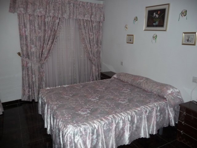 Charming bedroom with floral curtains and vintage decor in a village property in Zujar, Granada.