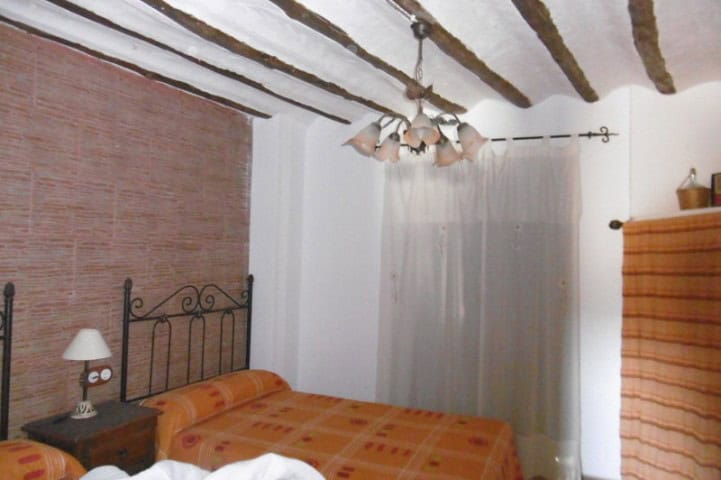 Charming bedroom in a village property in Hinojares, Jaen, featuring rustic ceiling beams and simple.