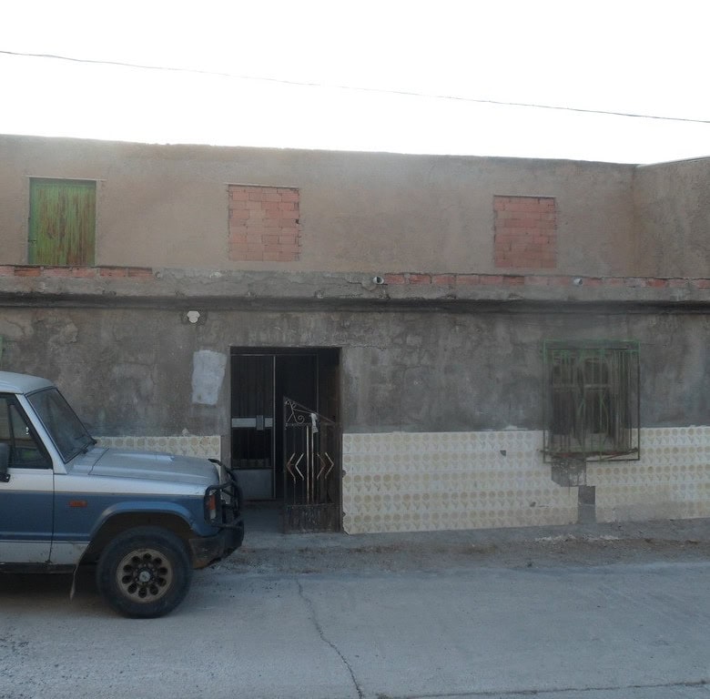 Village property in Freila, Granada featuring a traditional building with a parked car in front.