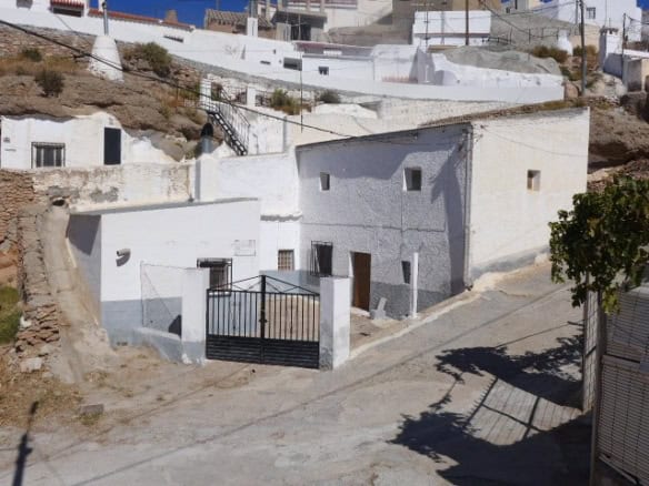 Cave house in Freila, Granada with whitewashed walls and a gated entrance.