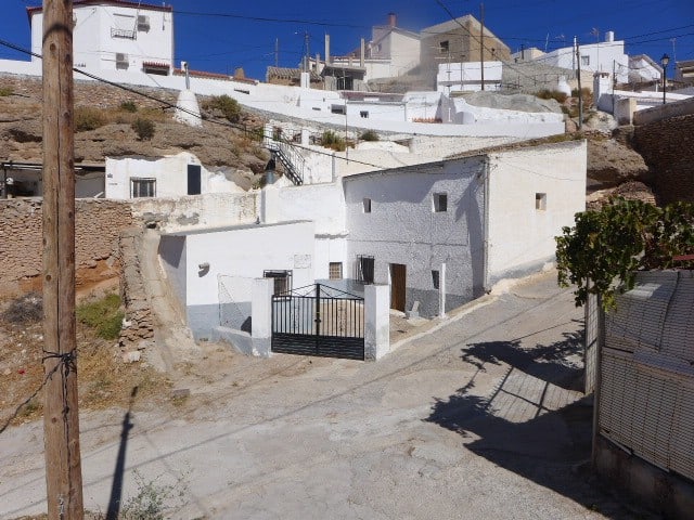 Traditional cave house in Freila, Granada with whitewashed walls and scenic hillside views.