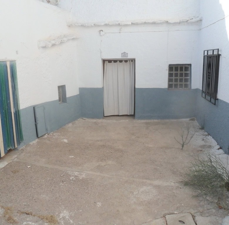 Cave house courtyard in Freila, Granada with white walls and simple doors.