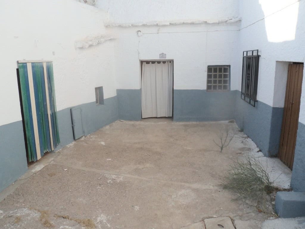 Cave house courtyard in Freila, Granada with white walls and simple doors.
