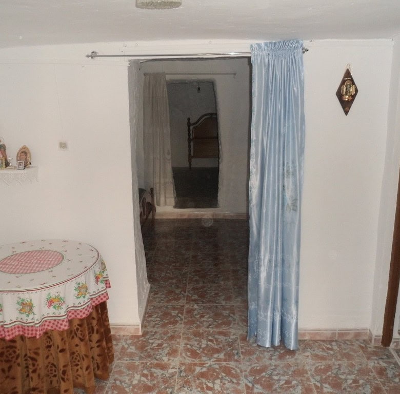 Cave house interior with simple furnishings in Freila, Granada, featuring a cozy living space and tr.