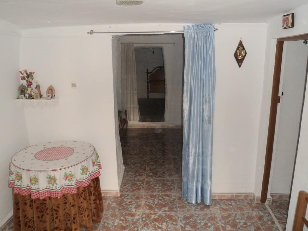 Cave house interior with simple furnishings in Freila, Granada, featuring a cozy living space and tr.