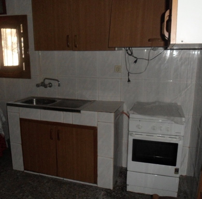 Cave house kitchen with basic appliances and wooden cabinets in Freila, Granada.