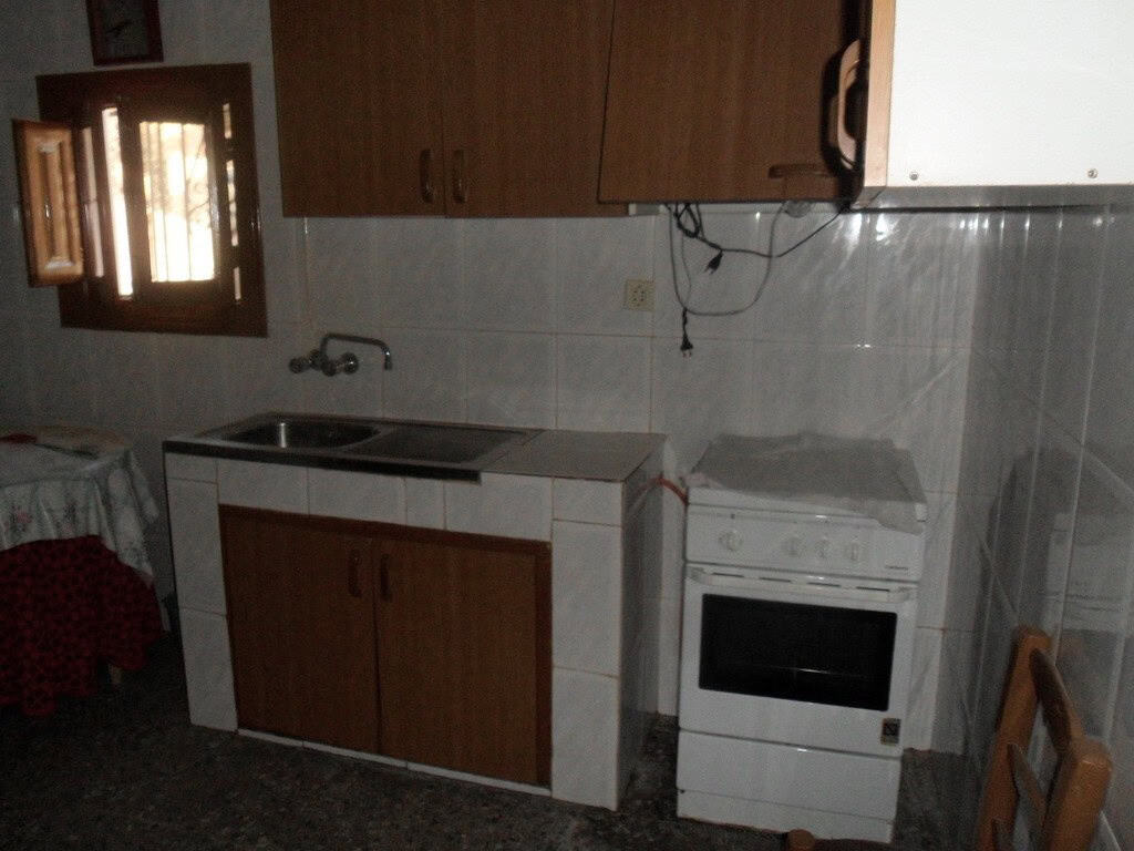 Cave house kitchen with basic appliances and wooden cabinets in Freila, Granada.