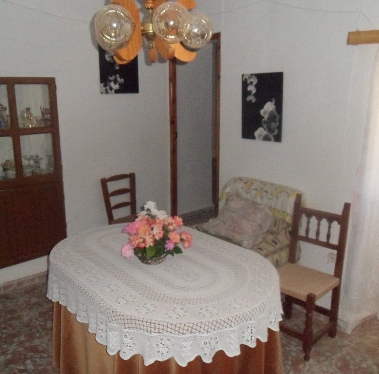 Charming cave house interior with dining table, vintage furniture, and decorative lighting in Freila.