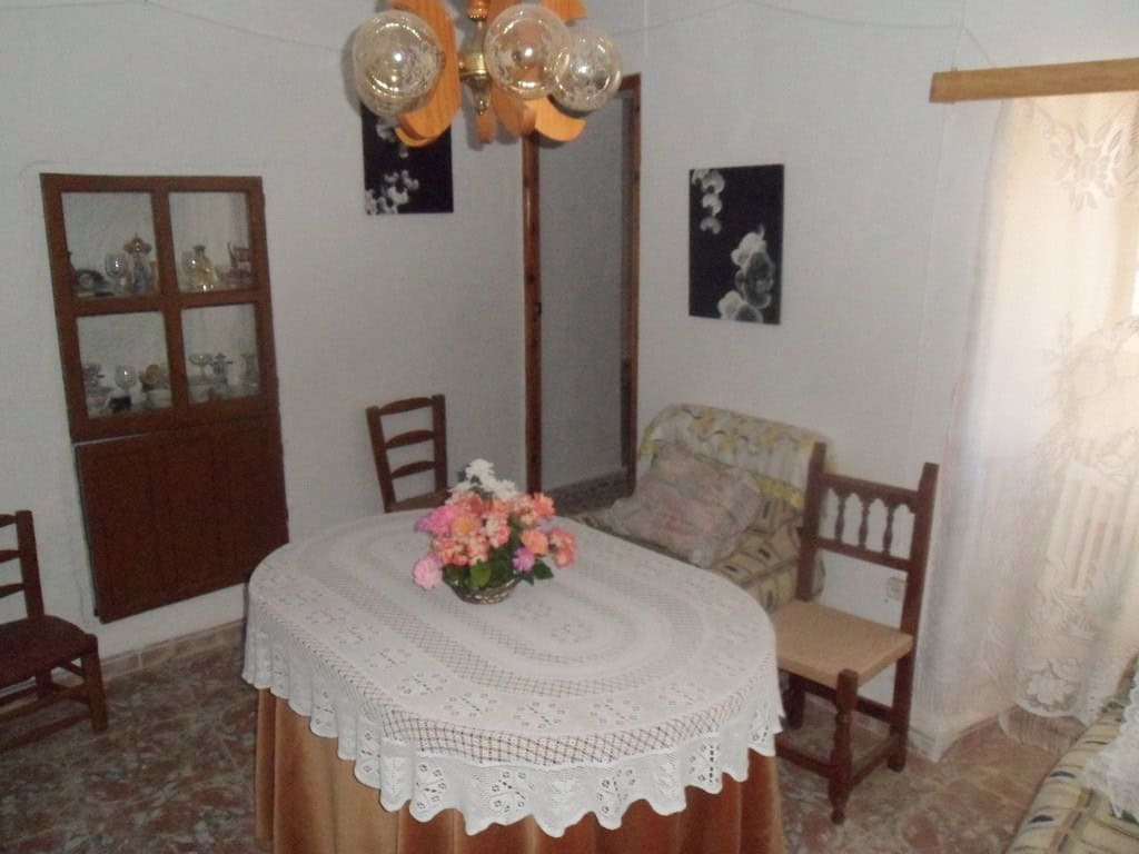 Charming cave house interior with dining table, vintage furniture, and decorative lighting in Freila.