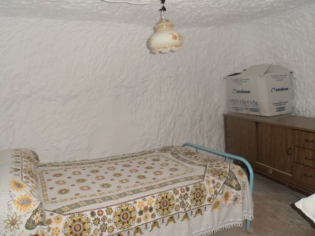 Interior of a traditional cave house in Freila, Granada with rustic furniture and vintage decor.