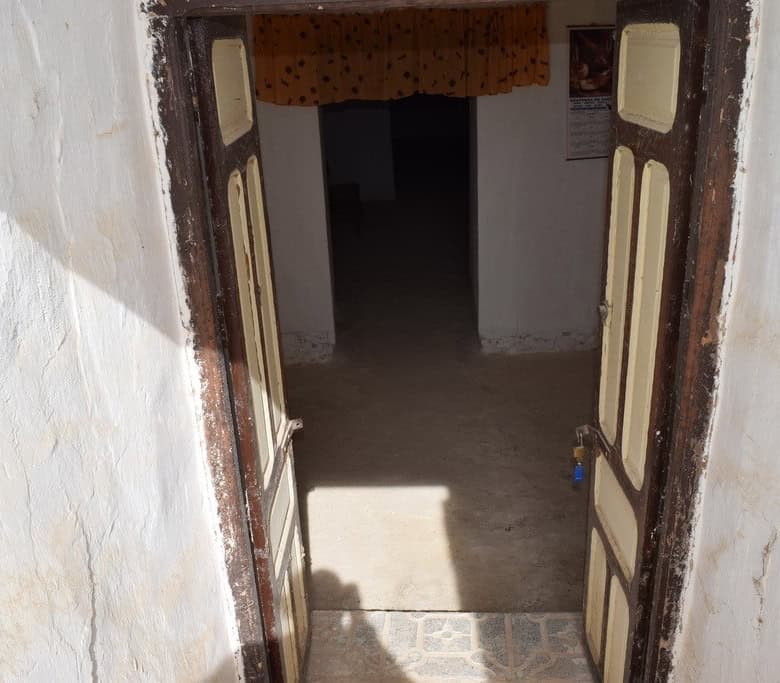 Traditional cave house entrance in Cuevas del Campo, Granada, showcasing rustic wooden doors and whi.
