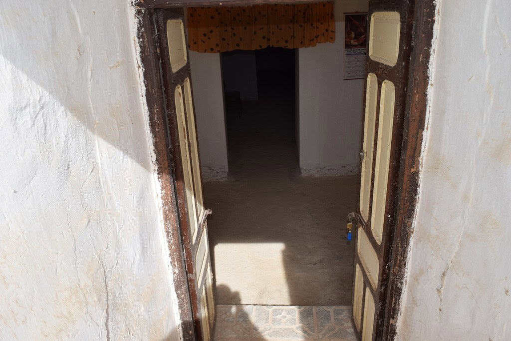 Traditional cave house entrance in Cuevas del Campo, Granada, showcasing rustic wooden doors and whi.