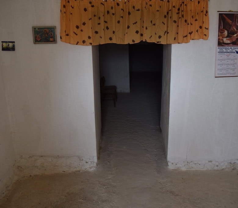 Entrance of a traditional cave house in Cuevas del Campo, Granada, with white walls and simple decor.