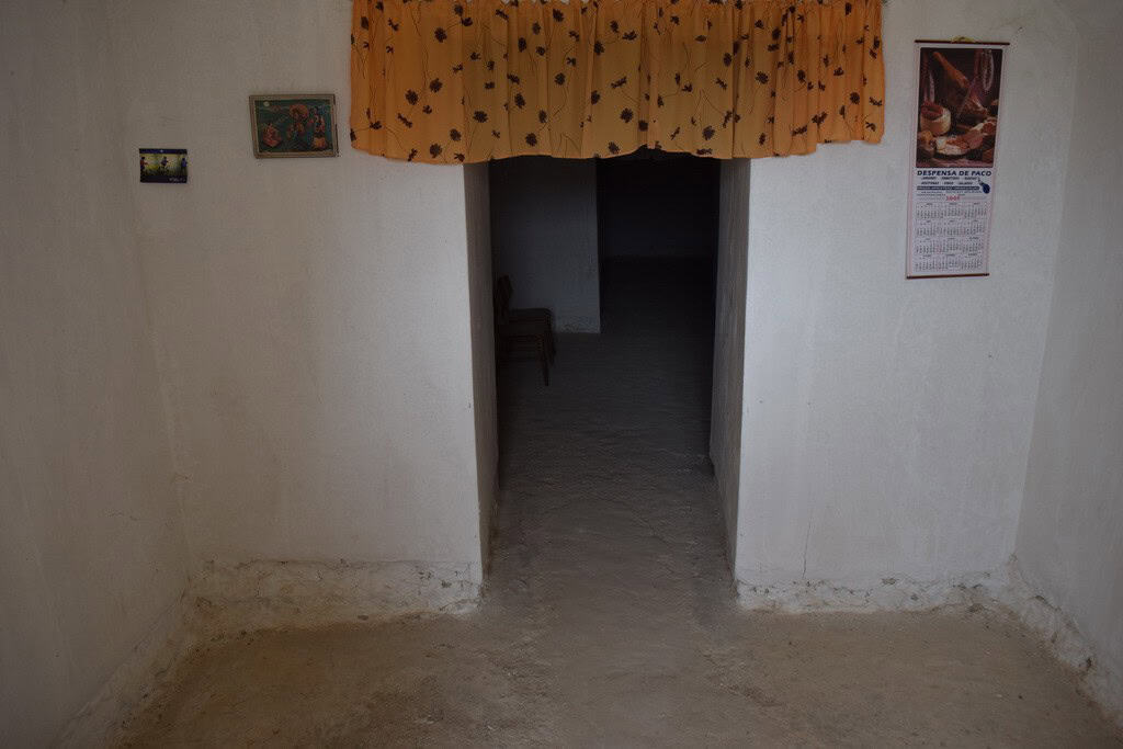 Entrance of a traditional cave house in Cuevas del Campo, Granada, with white walls and simple decor.
