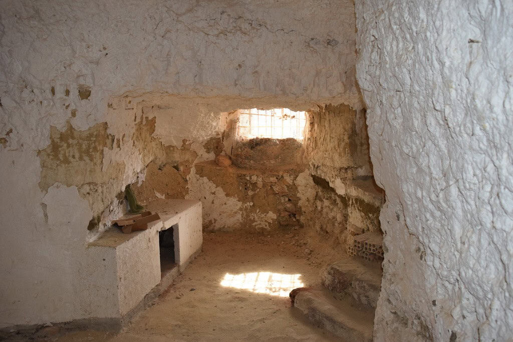 Interior view of a traditional cave house in Cuevas del Campo, Granada, showcasing rustic stone wall.