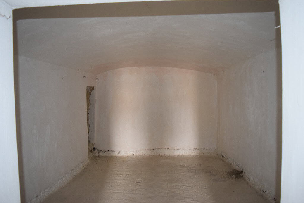 Cave house interior in Cuevas del Campo, Granada, with smooth white walls and arched ceiling.