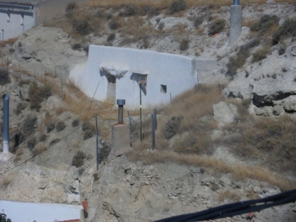 Cave house built into the hillside in Cuevas del Campo, Granada, with whitewashed walls and rugged t.
