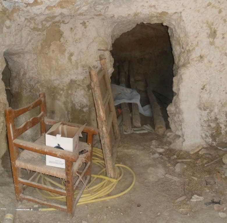 Interior of a historic cave house in Cuevas del Campo, Granada, showing rustic stone walls and entra.