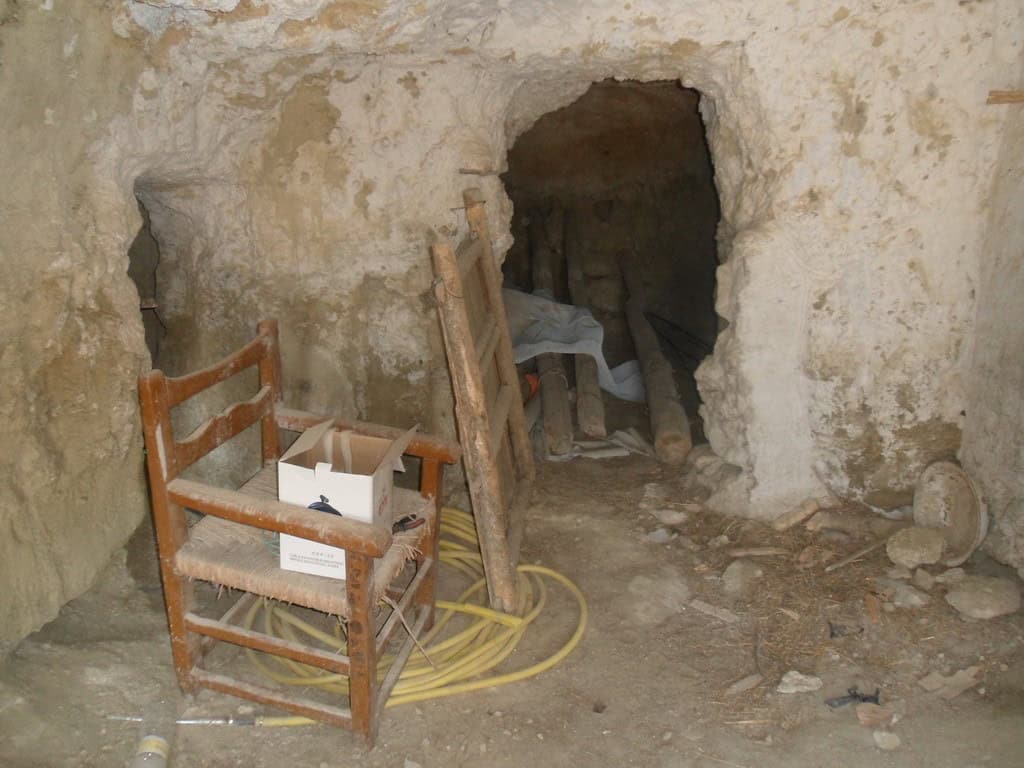 Interior of a historic cave house in Cuevas del Campo, Granada, showing rustic stone walls and entra.