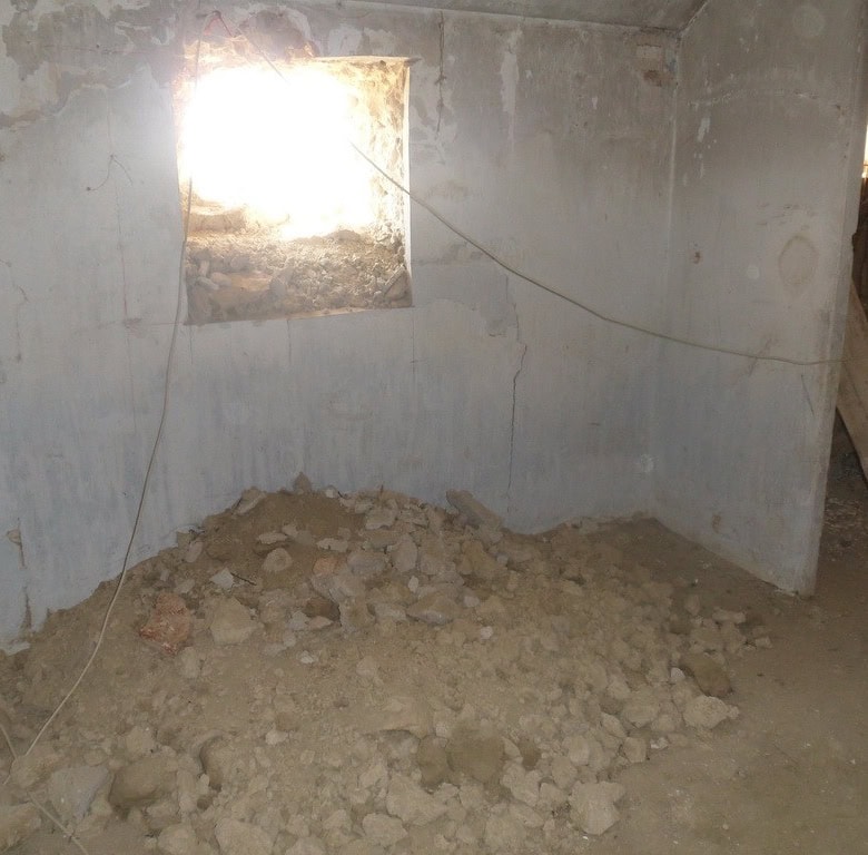 Cave house interior under renovation in Cuevas del Campo, Granada, with exposed walls and dirt floor.