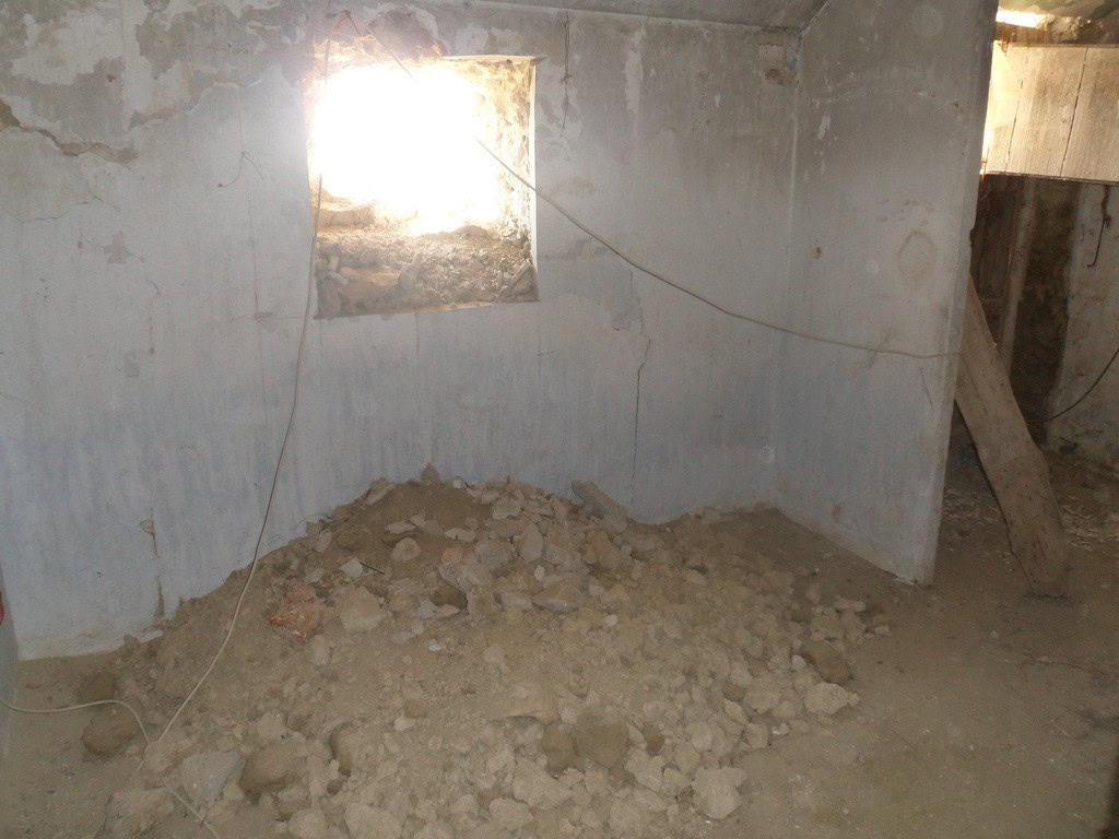 Cave house interior under renovation in Cuevas del Campo, Granada, with exposed walls and dirt floor.