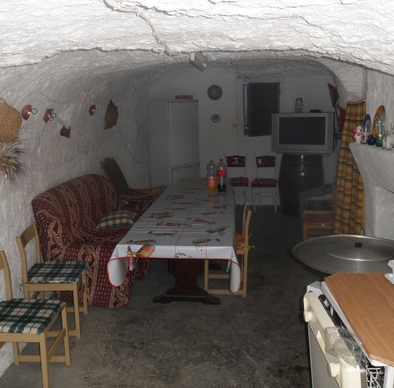 Traditional cave house interior with cozy seating and rustic decor in Cuevas del Campo, Granada.