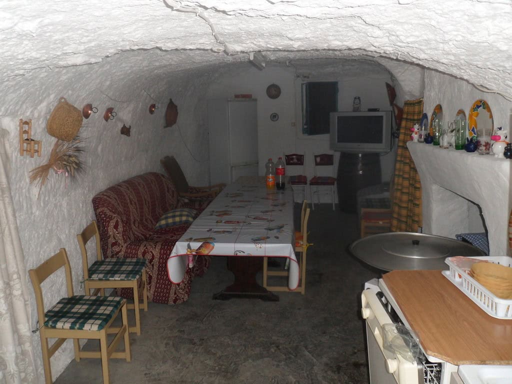 Traditional cave house interior with cozy seating and rustic decor in Cuevas del Campo, Granada.