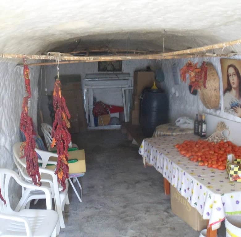 Cave house interior with traditional decor, hanging cured meats, and a cozy living space in Cuevas d.