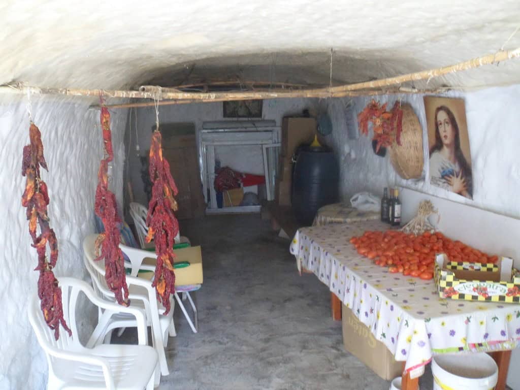 Cave house interior with traditional decor, hanging cured meats, and a cozy living space in Cuevas d.