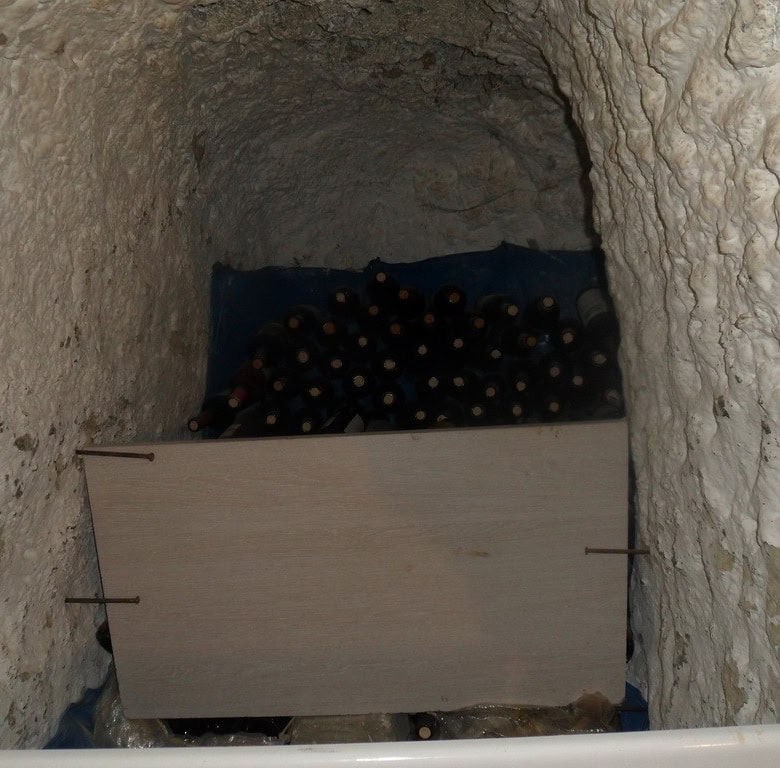 Cave house interior with wine bottles stored inside a natural rock cave in Cuevas del Campo, Granada.