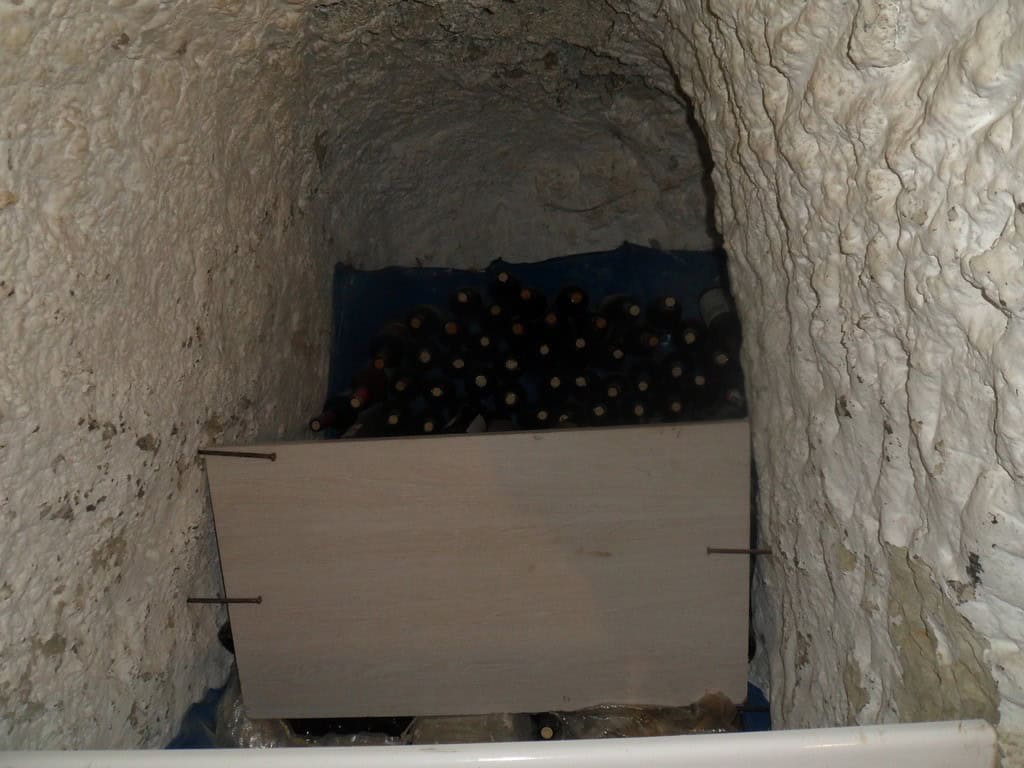 Cave house interior with wine bottles stored inside a natural rock cave in Cuevas del Campo, Granada.