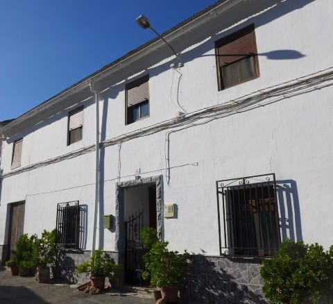 Town house with white exterior walls and black window bars in Fontanar, Jaen.