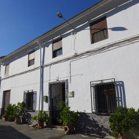 Town house with white exterior walls and black window bars in Fontanar, Jaen.