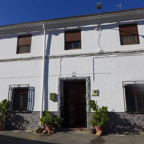 Charming town house in Fontanar, Jaen with white exterior, wooden shutters, and potted plants at the.