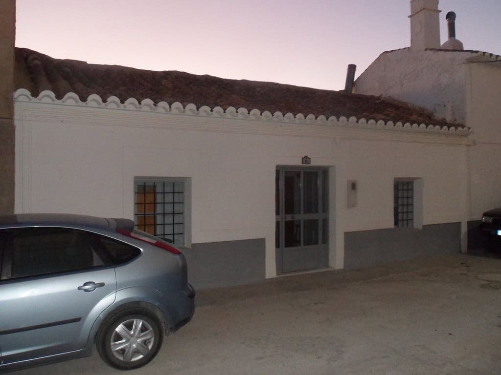 Cave house located in Freila, Granada, with traditional white exterior and surrounding vehicles.