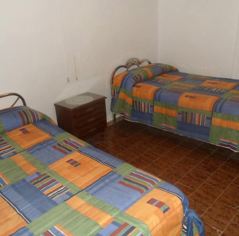 Cave house interior with two beds and colorful bedding in Freila, Granada.