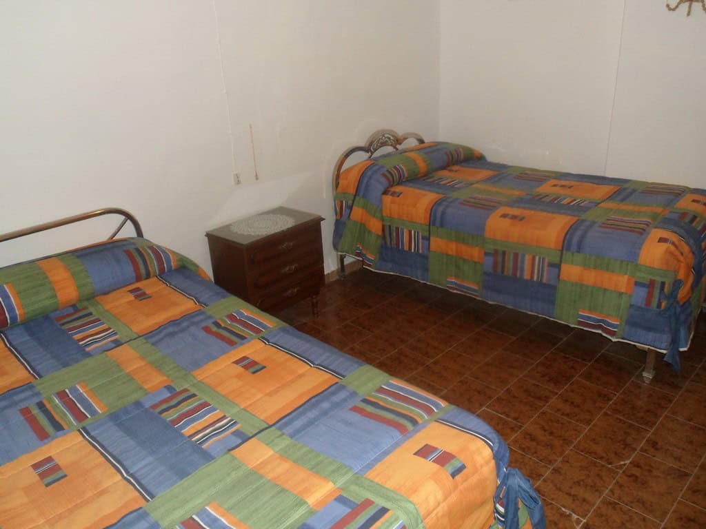 Cave house interior with two beds and colorful bedding in Freila, Granada.