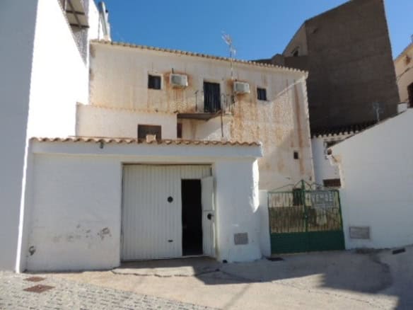 Cave house in Freila, Granada, with white exterior walls and small windows, set against a clear blue.