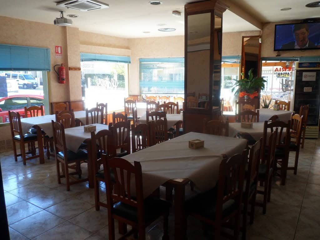 Interior of a cozy restaurant with wooden furniture and large windows in Cuevas del Campo, Granada.