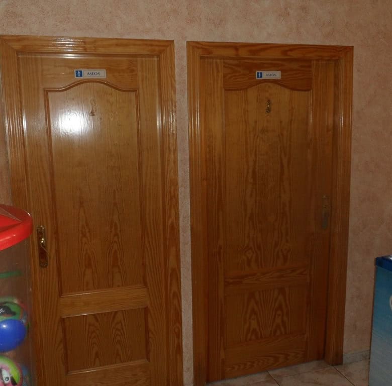 Commercial property doors in Cuevas del Campo, Granada, with wooden finishes and signage.